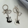 Guitares argentées et clés en forme de cœur avec un charm à étoile sur une surface blanche.