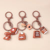 A set of brown coffee-themed keychains featuring various mugs and cups.