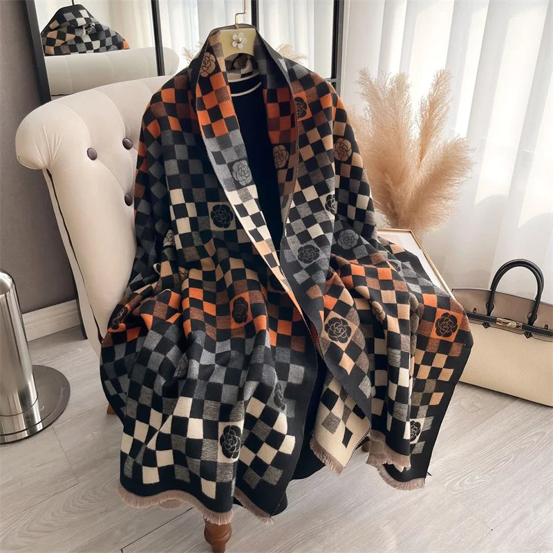 A dark plaid cashmere scarf and shawl wrap draped on a hanger in a bright room.