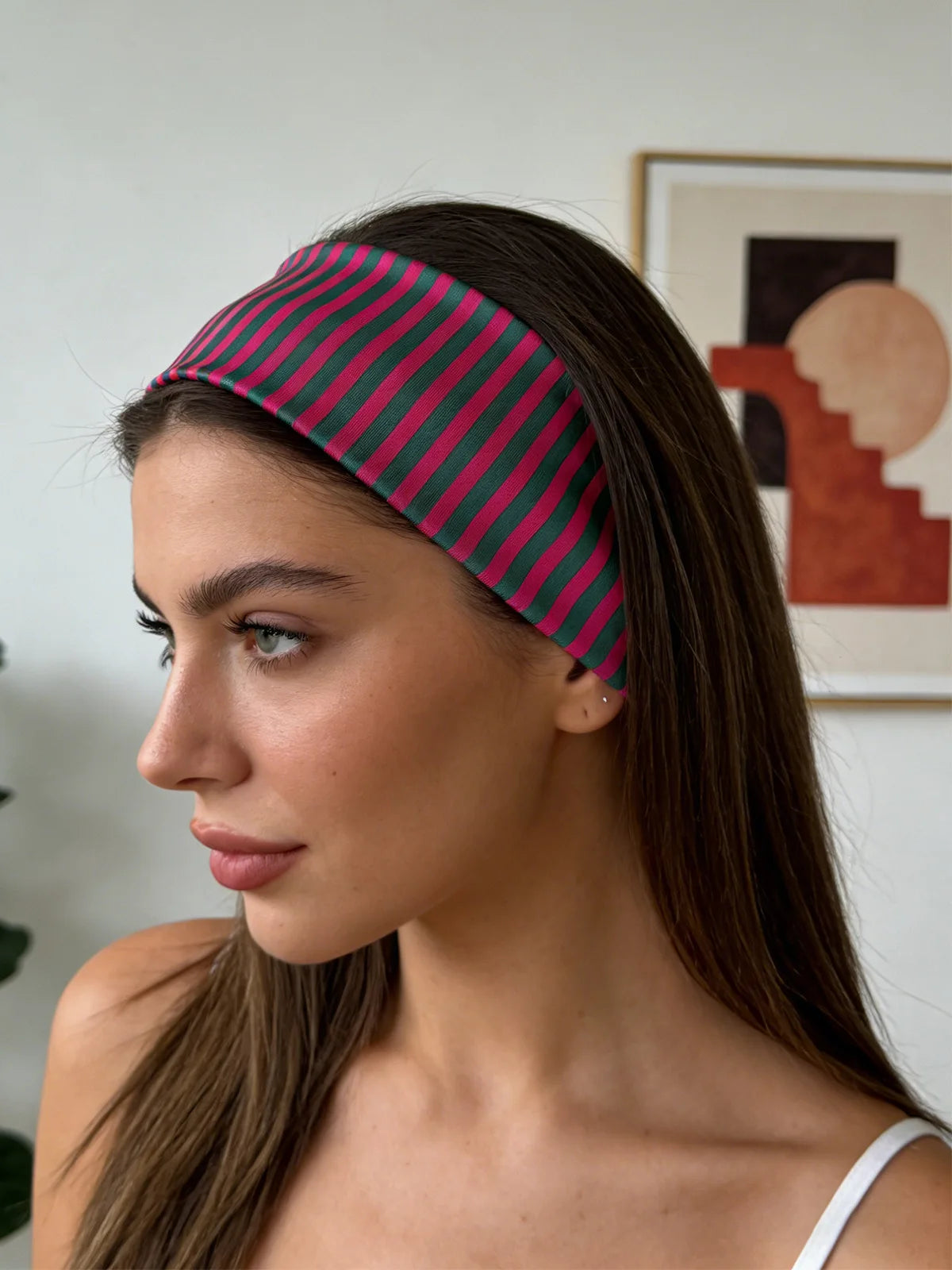 Une femme portant un élastique à cheveux rayé rose et noir sur ses cheveux foncés.