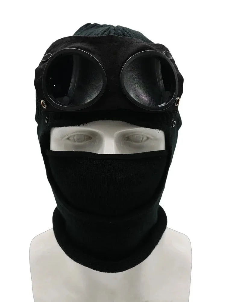 Black knit windproof hat with large circular goggles worn on a mannequin head.