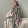 Una mujer vistiendo un elegante pañuelo de hijab a rayas y un vestido de color claro.