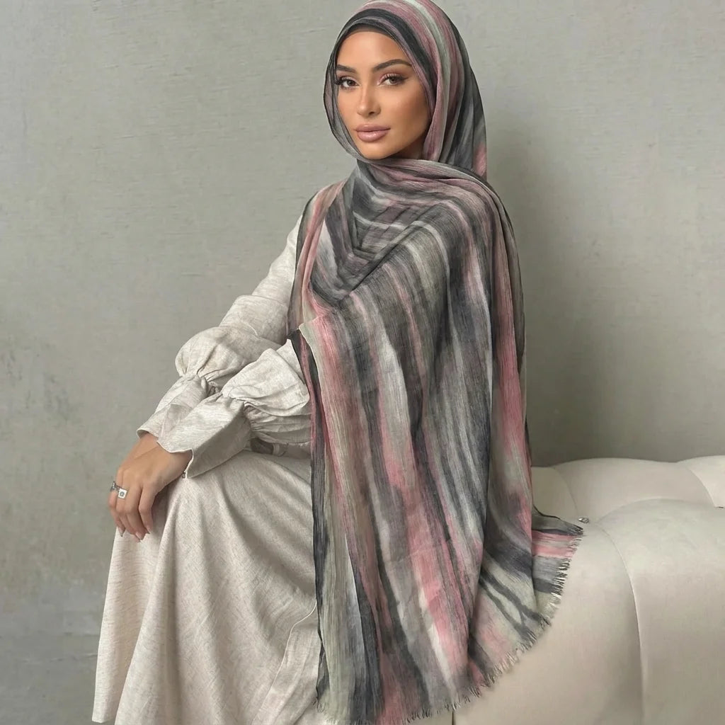 Una mujer vistiendo un elegante pañuelo de hijab a rayas y un vestido de color claro.
