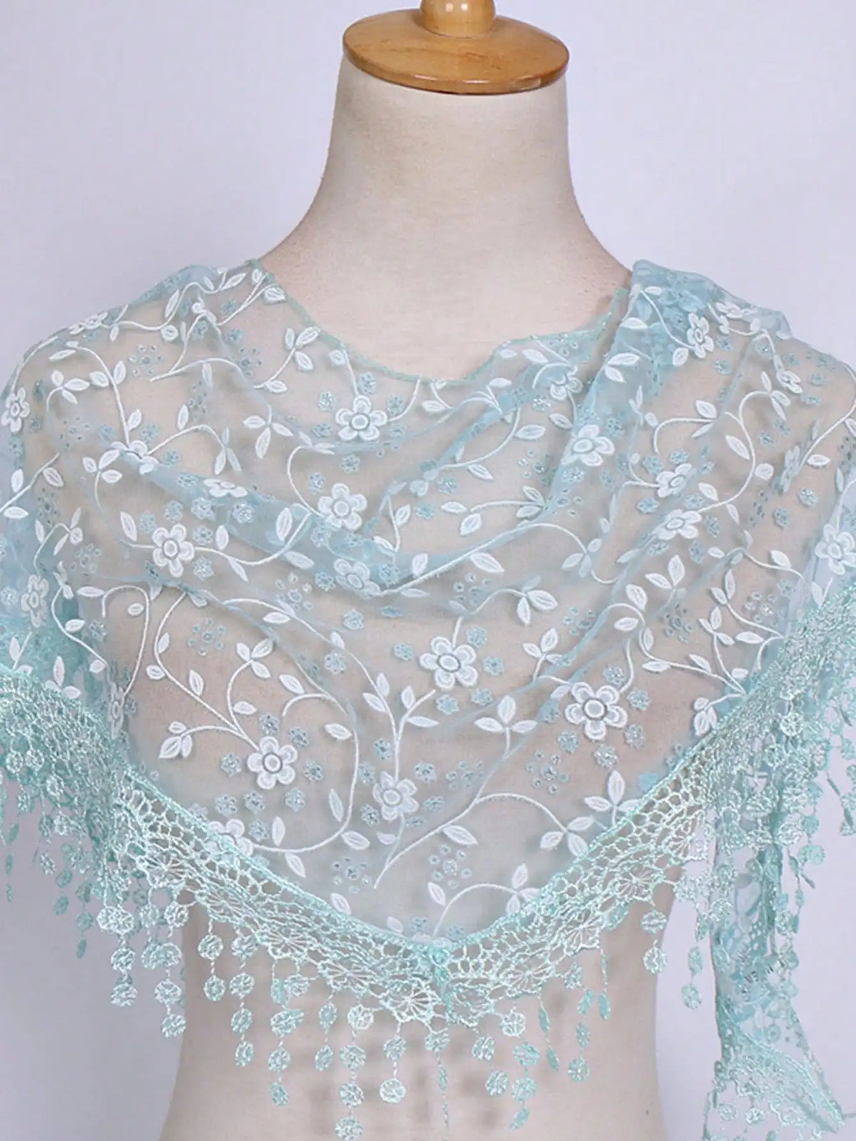 A sheer light blue floral lace scarf draped around a mannequin's neck and shoulders.
