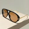 Black aviator style sunglasses with gold accents resting on a white surface.