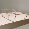 Un par de gafas de computadora metálicas finas, tono dorado con acentos rosados, sobre una superficie blanca.