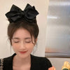 Una mujer usando una pinza para el pelo de lazo negro con un elegante patrón vintage de anacardo en su cabello.