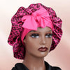 A pink satin sleep bonnet with a leopard print pattern tied in a bow, displayed on a mannequin head.