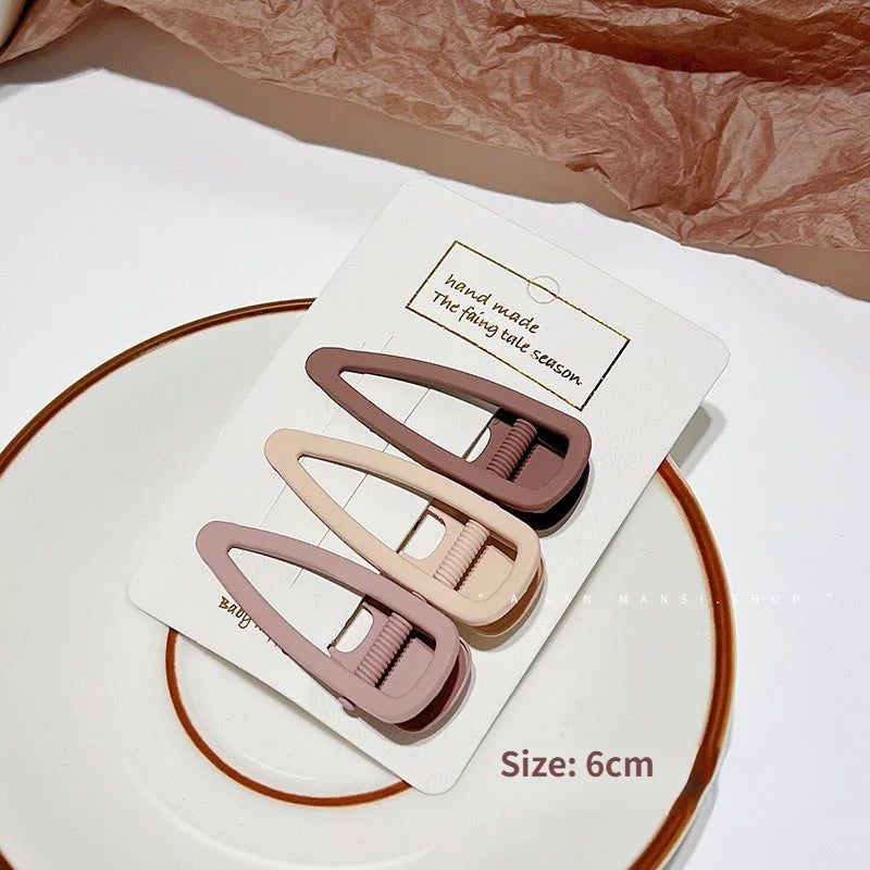 A set of vintage frosted geometry hair clips in a dusty rose color displayed on a white card.