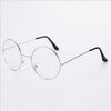 Un par de gafas redondas de metal anti-luz azul con patillas negras delgadas sobre un fondo blanco.