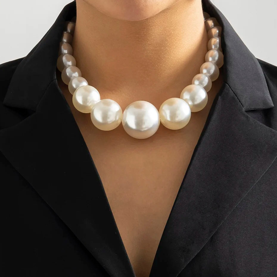 Gros plan d'un élégant collier imitation perles porté autour du cou sur un blazer noir.