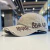 A light beige vintage washed cotton baseball cap with embroidered text on the front