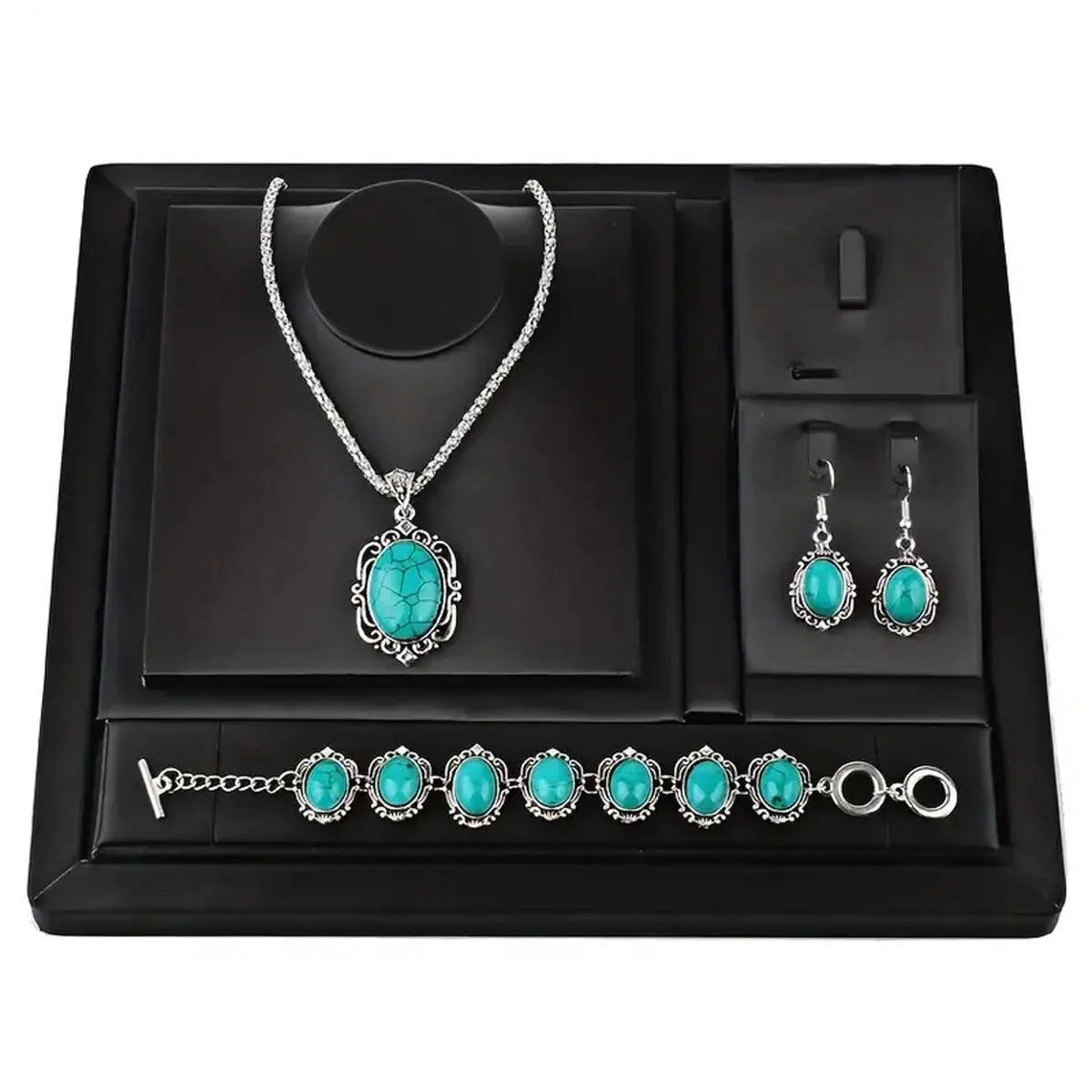 A black jewelry display box featuring a silver necklace, earrings, and bracelet set with turquoise stones.