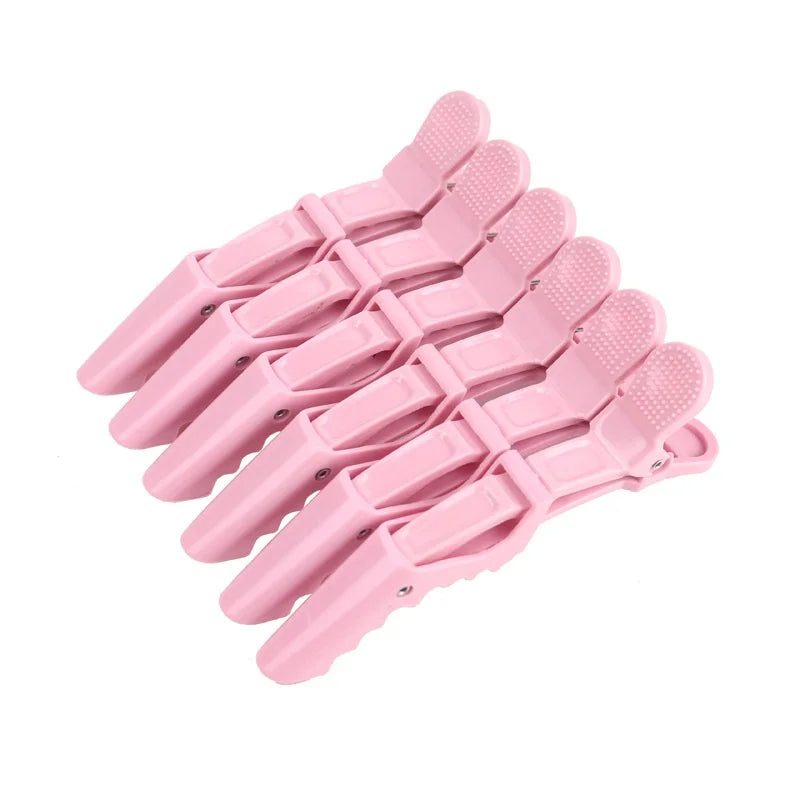 A set of six pink alligator hair sectioning clips arranged in a row.