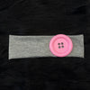 A pink silicone hairband with small holes is placed on a gray fabric band against a black background.