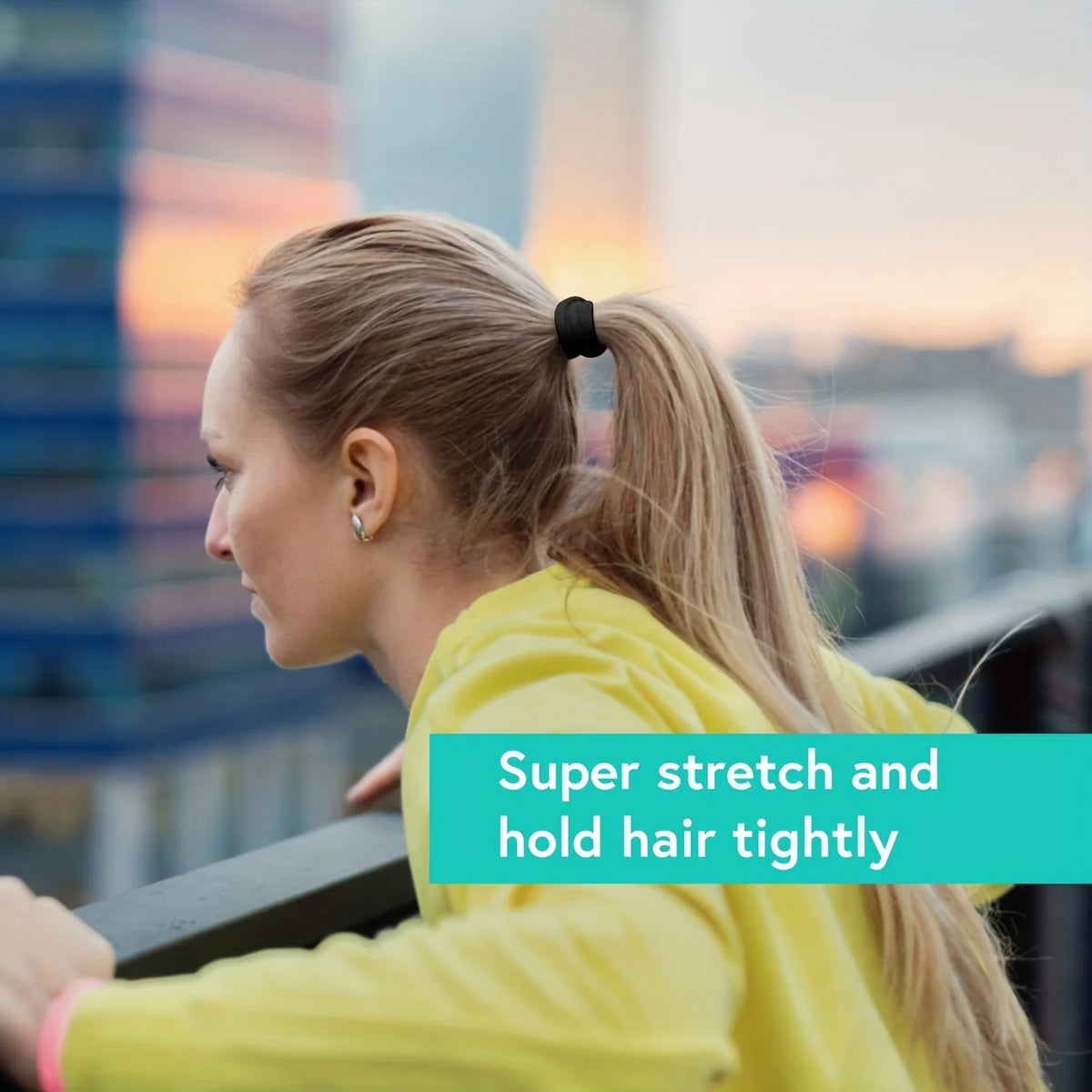 A woman with blonde hair is performing a stretch while holding her hair tightly with elastic bands.