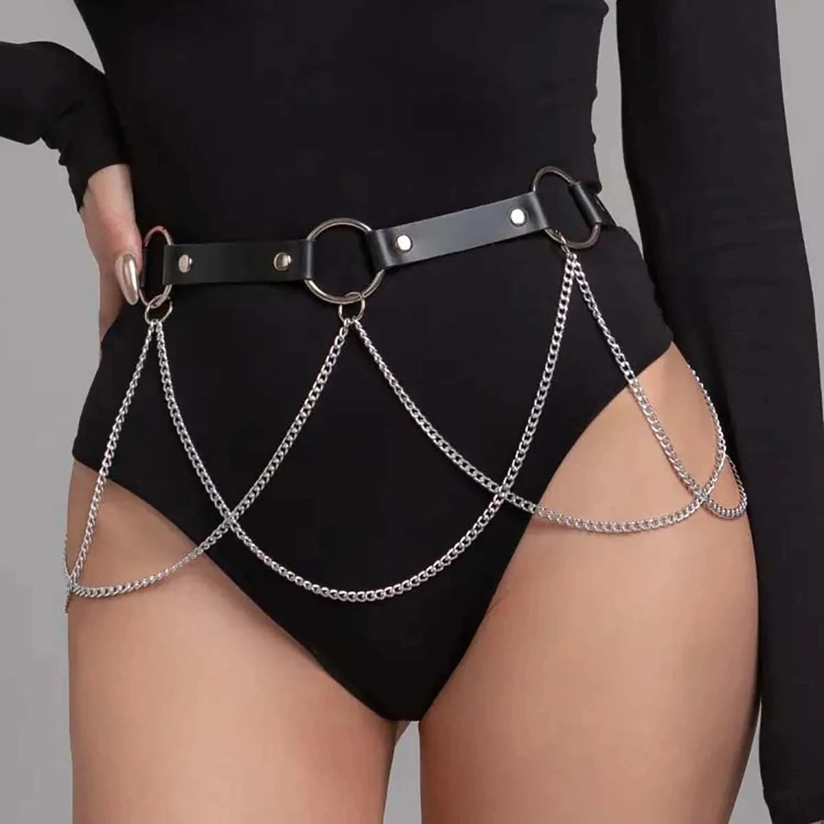 Un cinturón arnés de cuero sintético negro con cadenas plateadas y correas de cuero usado alrededor de la cintura de una mode