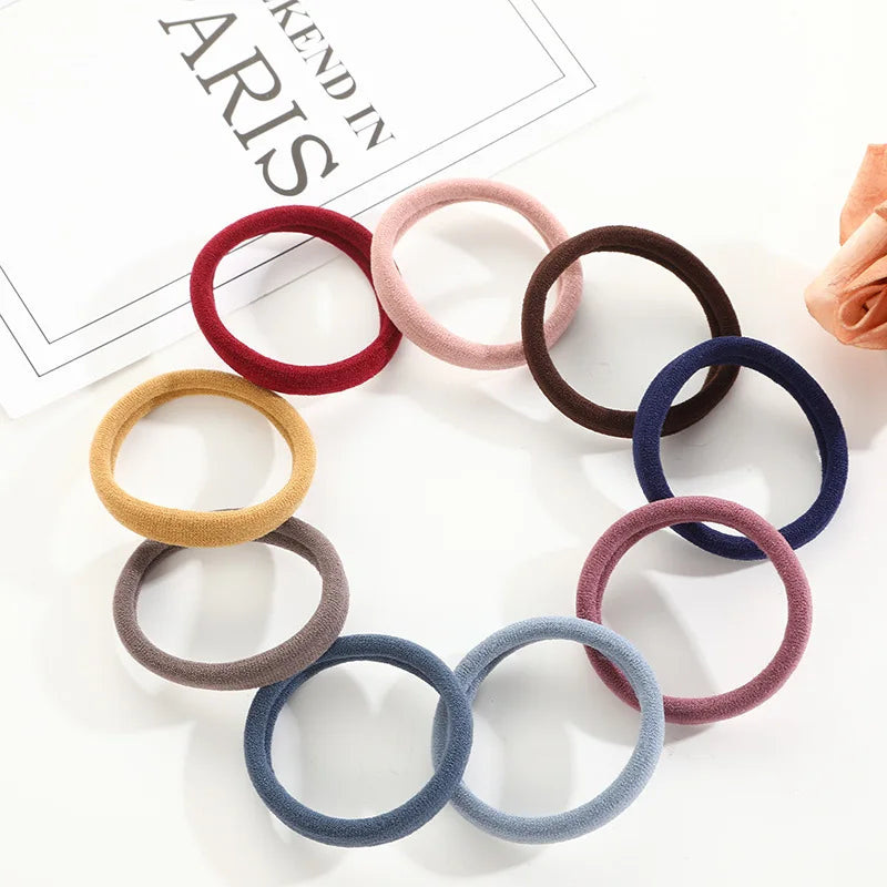 A collection of ten elastic hair ropes in various shades of pink, brown, and blue arranged on a white background.