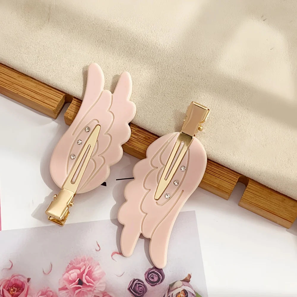 A pair of pink angel wing hair clips and barrettes displayed on a light background.
