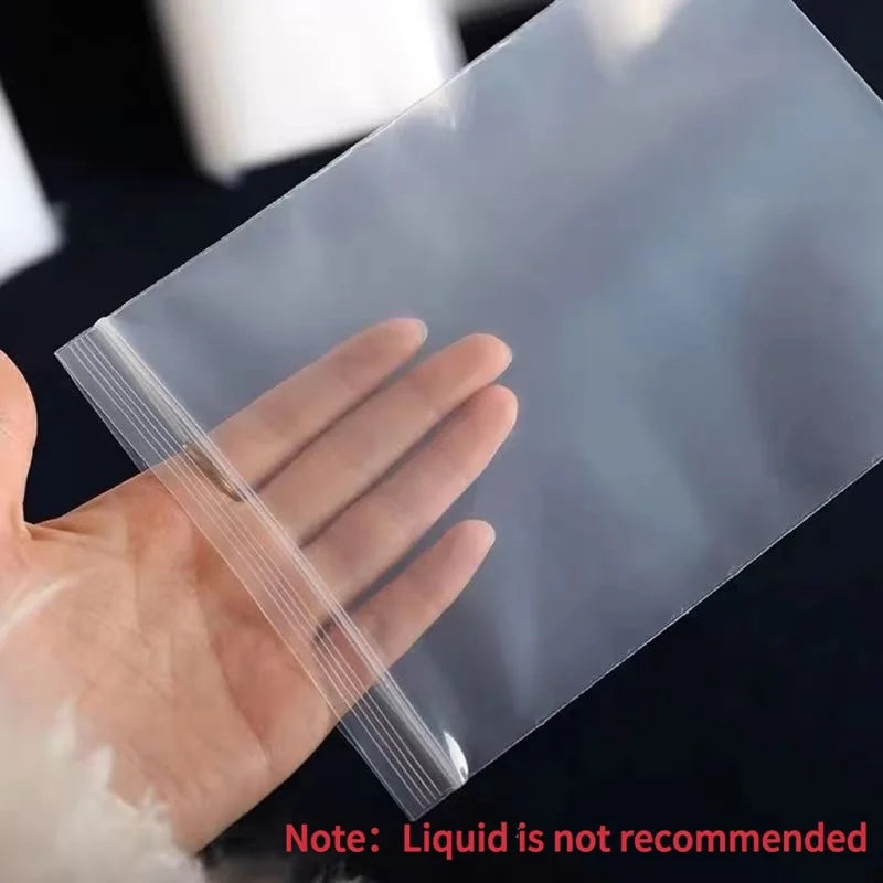 A hand is holding a clear reusable ziplock storage bag, demonstrating the product's transparency and flexible plastic.