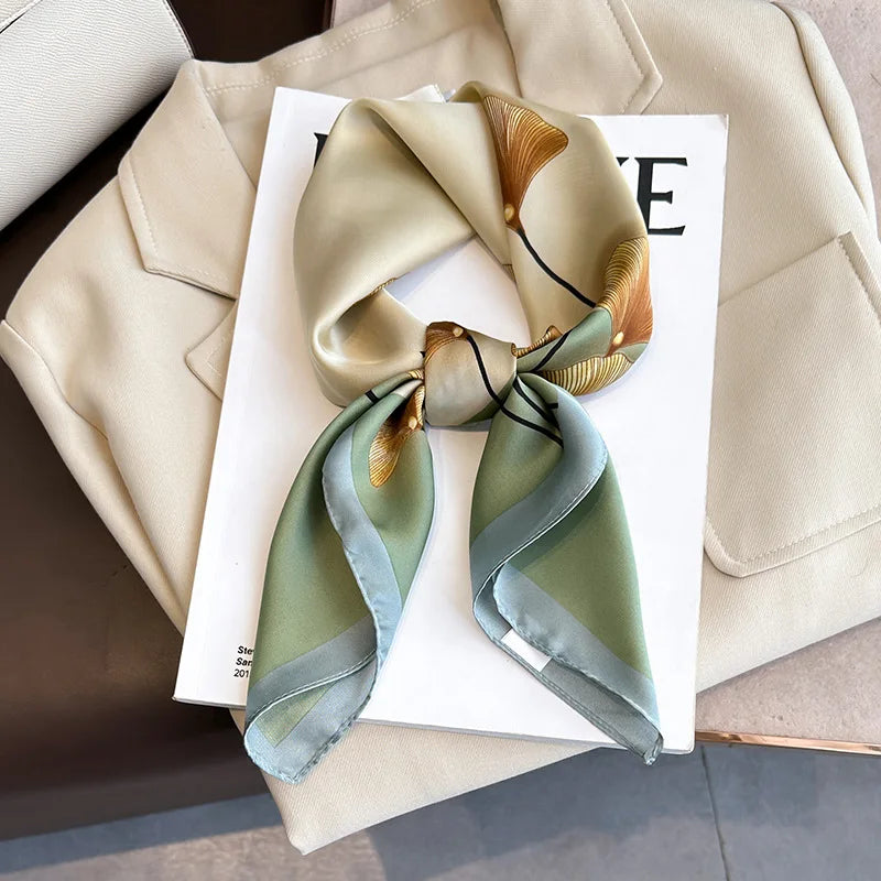 A silk scarf tied in a bow with gold accents, displayed on a white card against a beige blazer.
