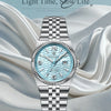 A silver-toned luxury quartz women's wristwatch with a light blue dial and luminous features resting on draped fabric.