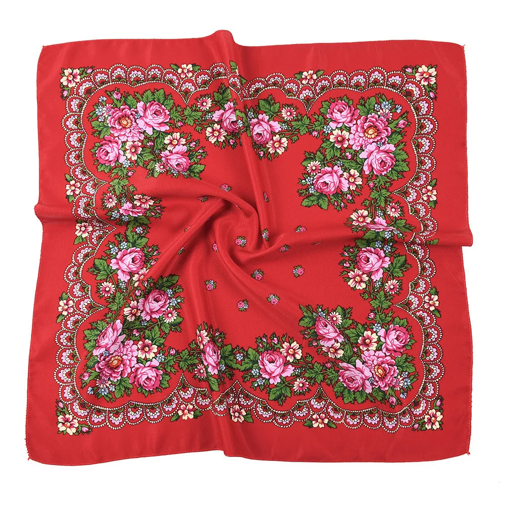 A vibrant red silk scarf featuring an intricate floral print with pink and green roses.