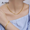 A gold plated chain necklace worn by a woman against a light blue shirt.