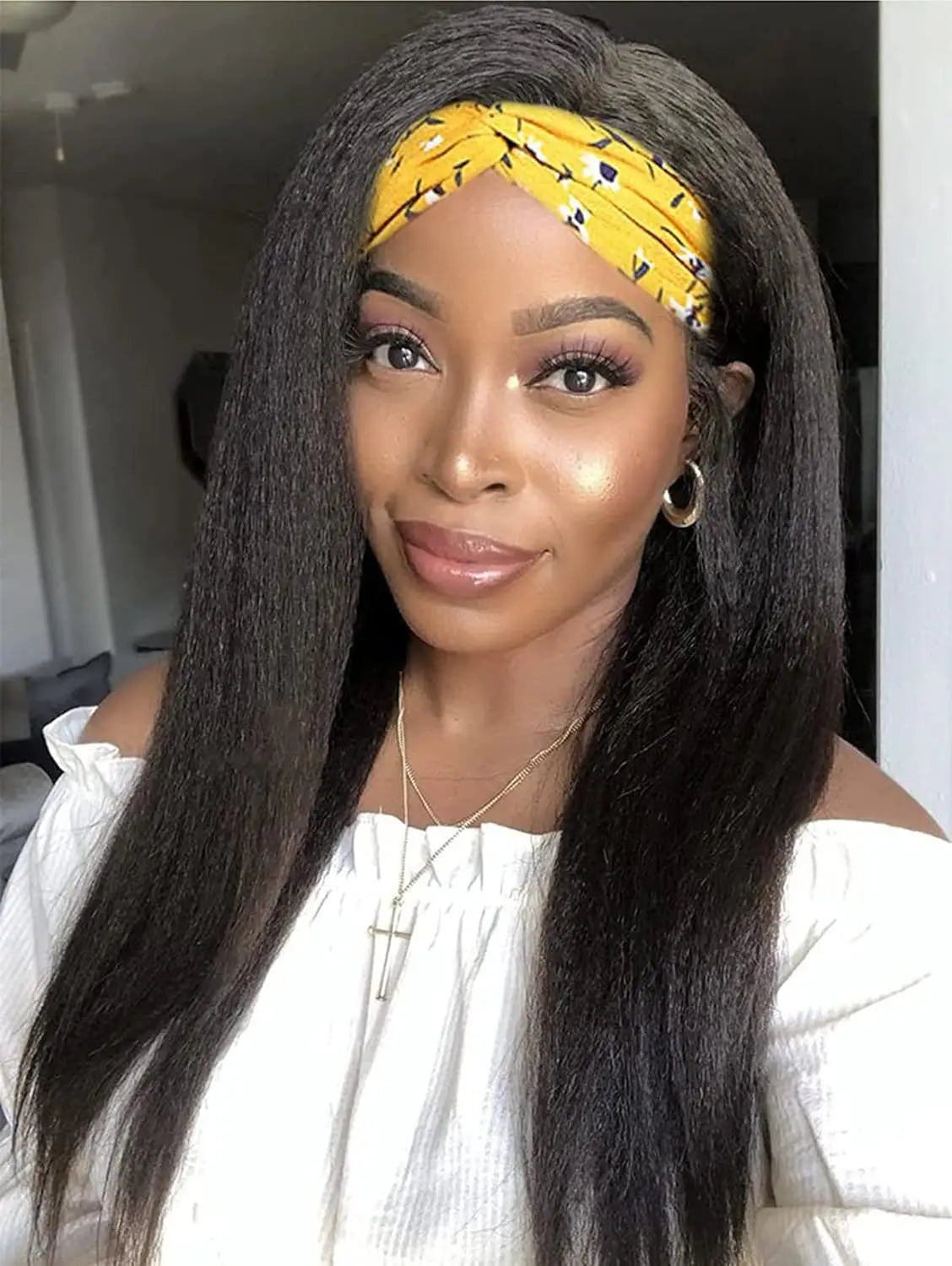 A woman with long straight black hair wearing a yellow patterned headband and a white top.