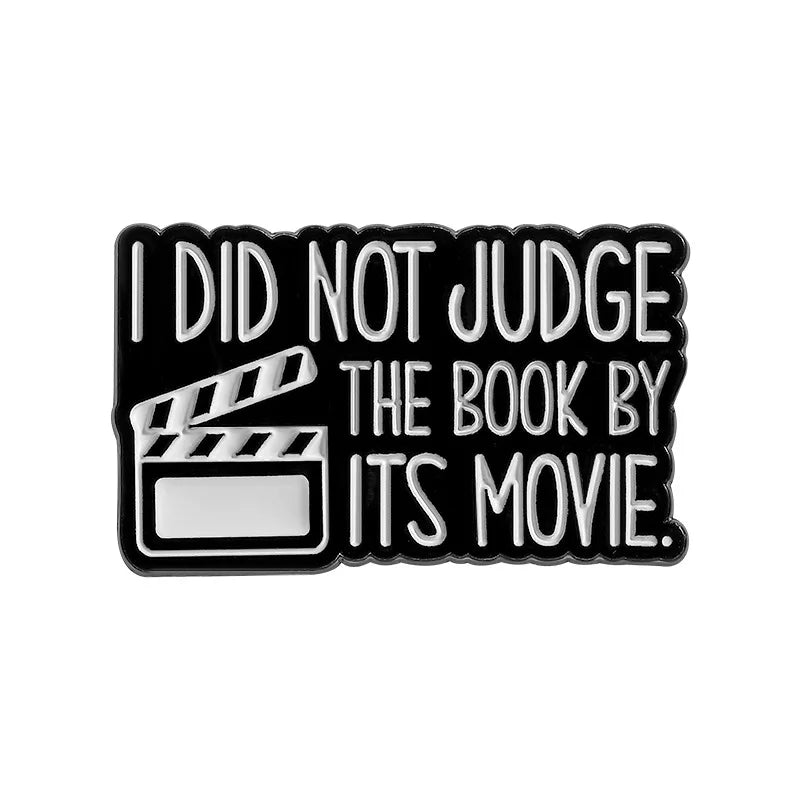 Black enamel lapel pin with white text that reads I DID NOT JUDGE THE BOOK BY ITS MOVIE
