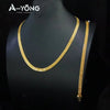 A gold plated necklace set displayed on a black mannequin.