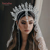 A woman wearing a sparkling rhinestone bridal crown headband and lace veil.