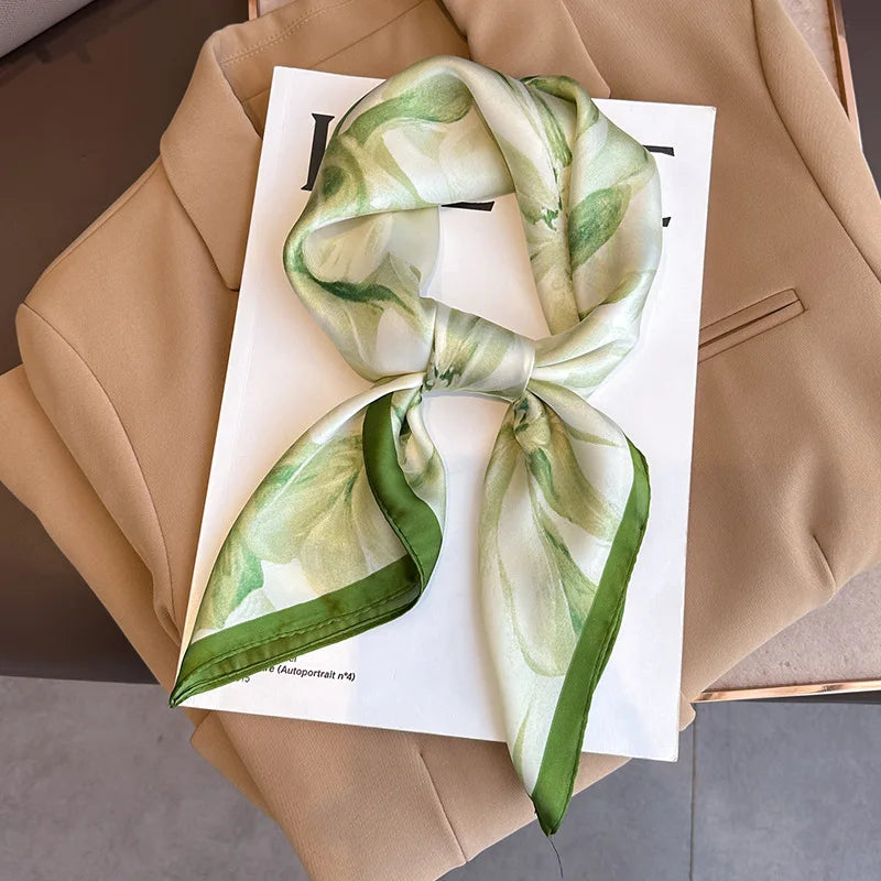 A light green and white floral silk scarf tied in a bow, displayed on a beige blazer.