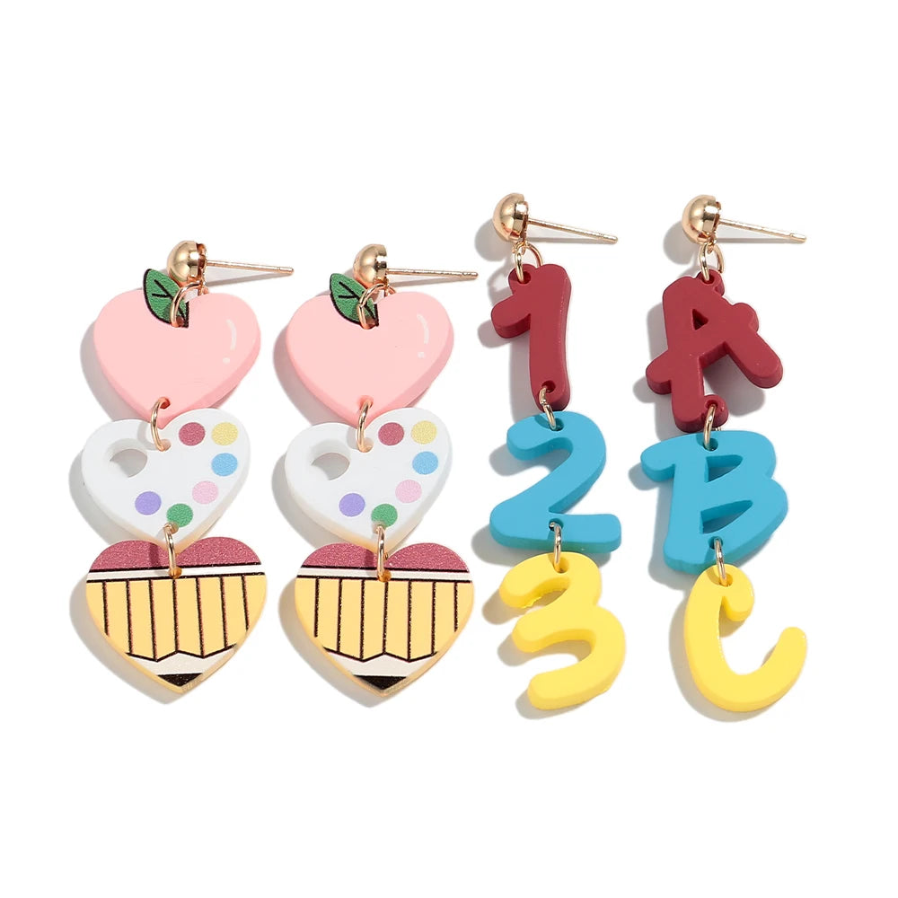 Un par de pendientes colgantes con forma de los números 1, A y B en colores rosa, rojo y azul.