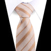 A close-up of an elegant men's floral paisley silk necktie in beige and white diagonal stripes worn under a white shirt.