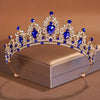 Diadema de tiara de cristal azul brillante y transparente con intrincado diseño barroco, mostrada en una caja.