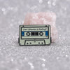 A retro fine line cassette enamel pin brooch with the text Can I Borrow a Feeling on a light pink background.