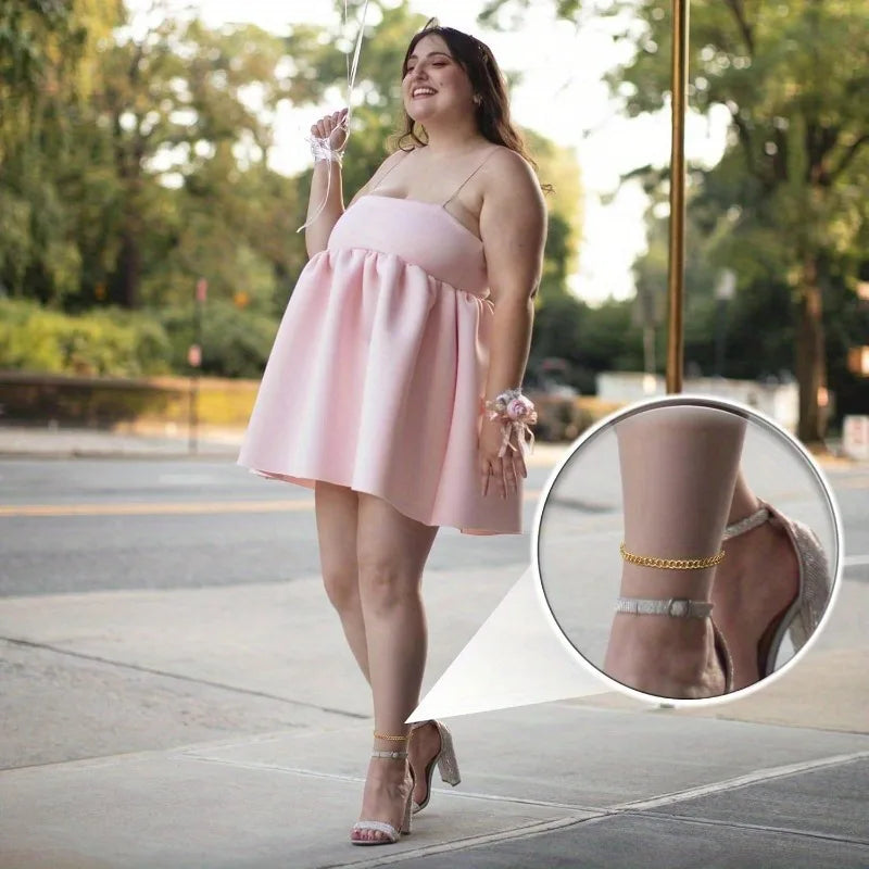 A woman models a pink dress and gold snake chain anklets outdoors.