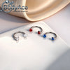 A set of titanium steel nose rings featuring red and blue cubic zirconia crystals displayed on a white surface.