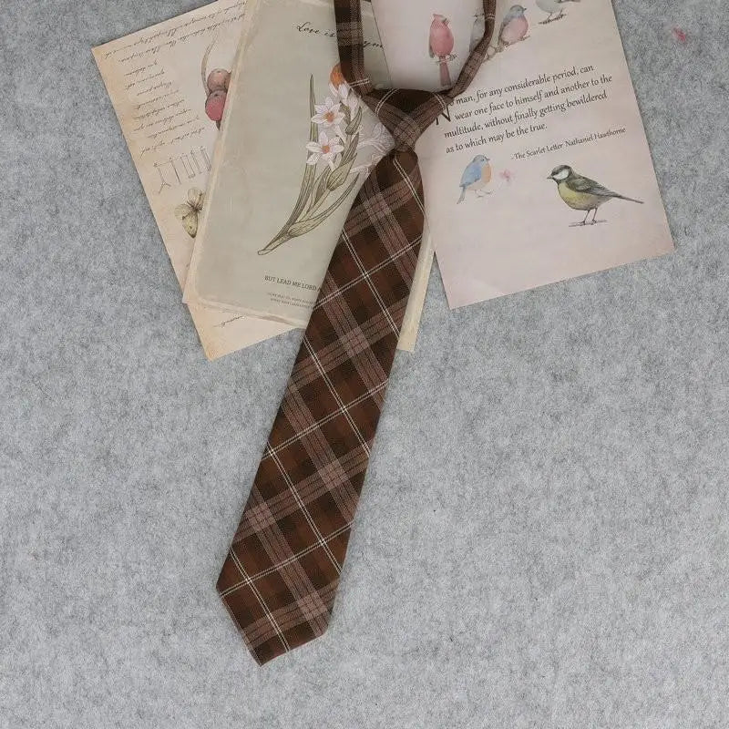 A stack of Japanese plaid neck ties with floral and bird patterns resting on a gray fabric background.