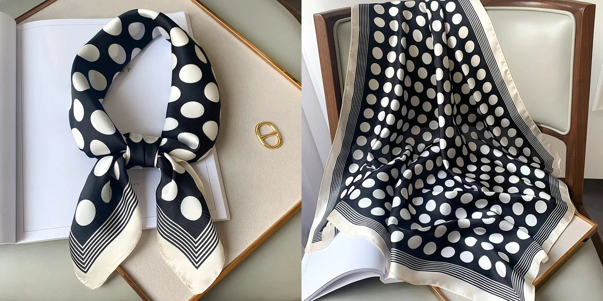 A black and white polka dot silk scarf tied in a bow with striped edges displayed next to a book.