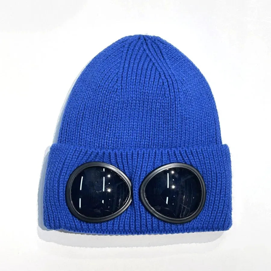 A royal blue knit hat with round black goggles attached to the front