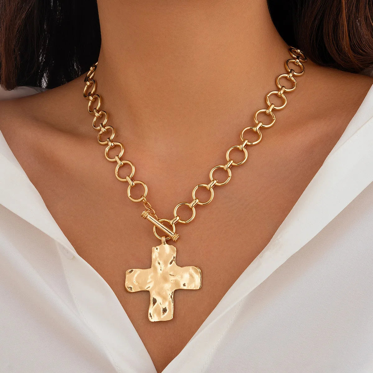 Nahaufnahme einer 18k-Gold-Gliederkreuz-Anhänger-Kette um den Hals, getragen über einem weißen Hemd.