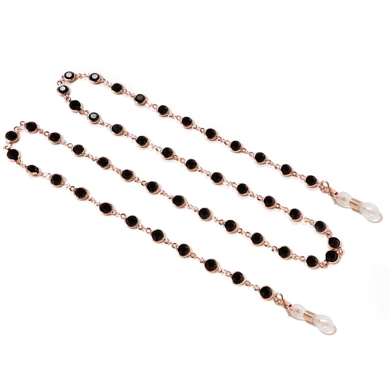 A delicate rose gold chain with black beads and pearl accents used as a lanyard for sunglasses.