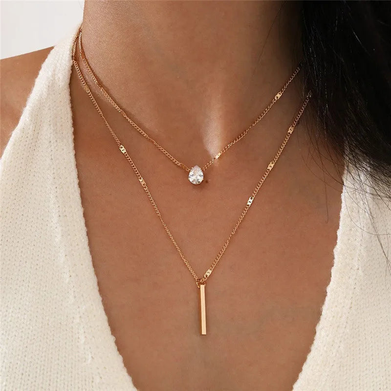 Un collier de perles minimaliste en or porté au cou d'une femme sur un fond neutre.