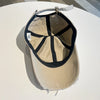 A vintage washed cotton baseball cap with a light tan crown and black embroidered letter detail.