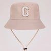 A light beige sun hat with a large white letter G embroidered on the front.