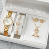 A white box contains an elegant gold-toned quartz wristwatch, a gold-toned pendant necklace set, and other jewelry pieces.