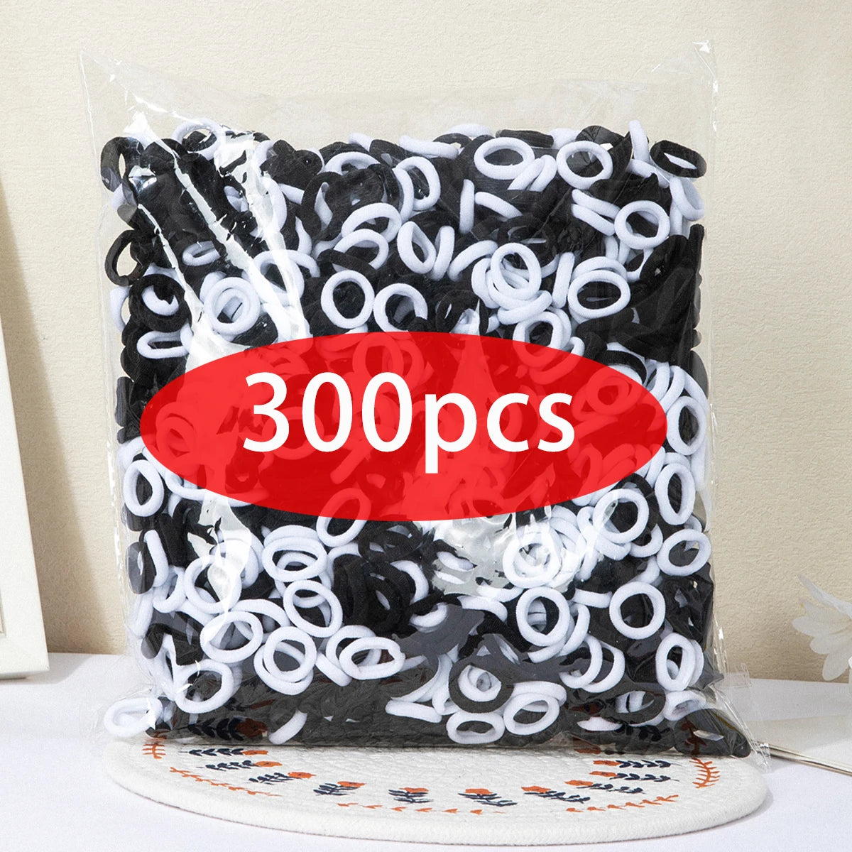 A clear plastic bag filled with 300 pieces of black and white nylon elastic hair cords.