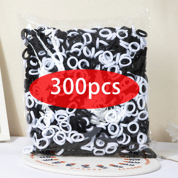 A clear plastic bag filled with 300 pieces of black and white nylon elastic hair cords.